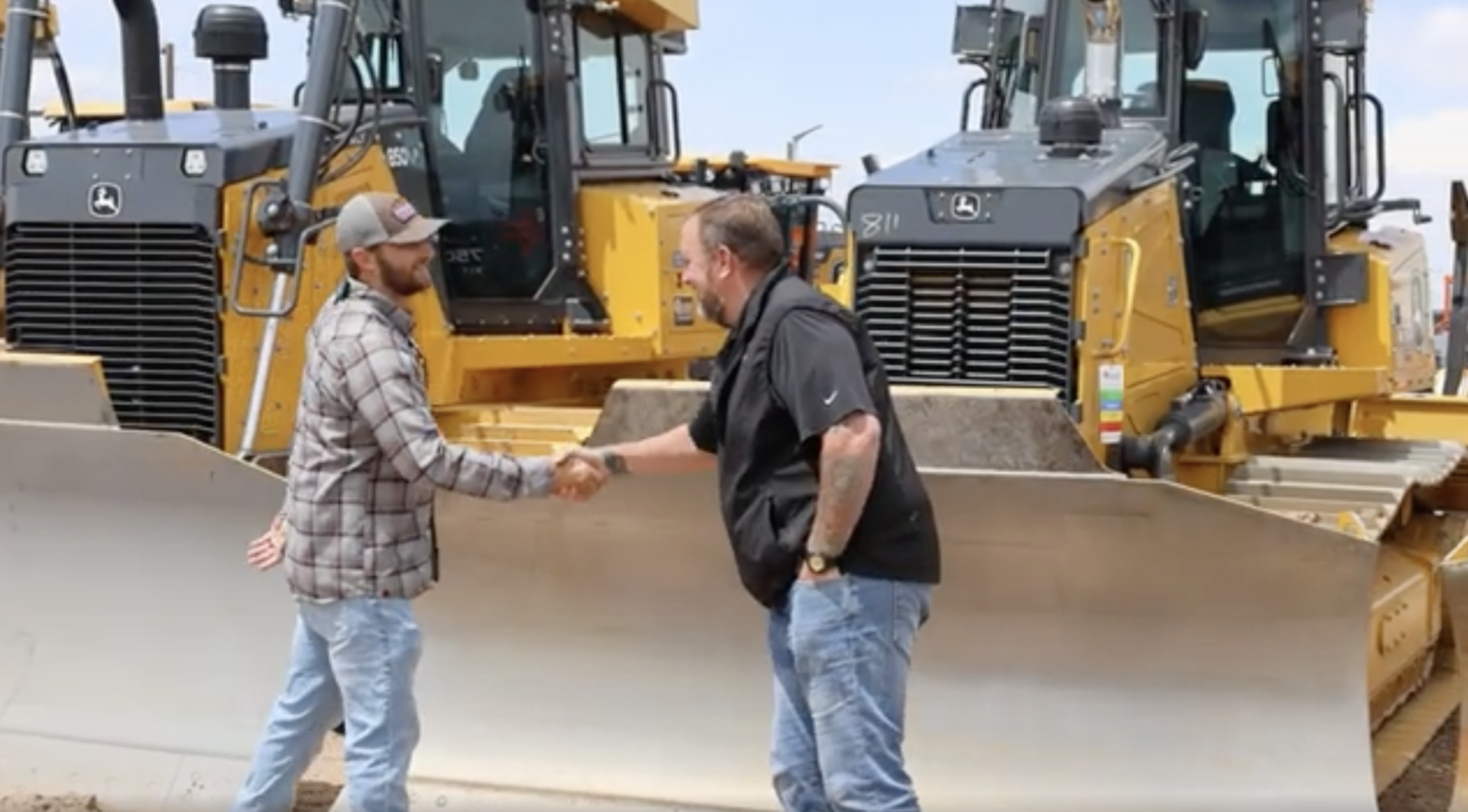 AUI Inc and 4Rivers personnel shaking hands in front of some heavy equipment.